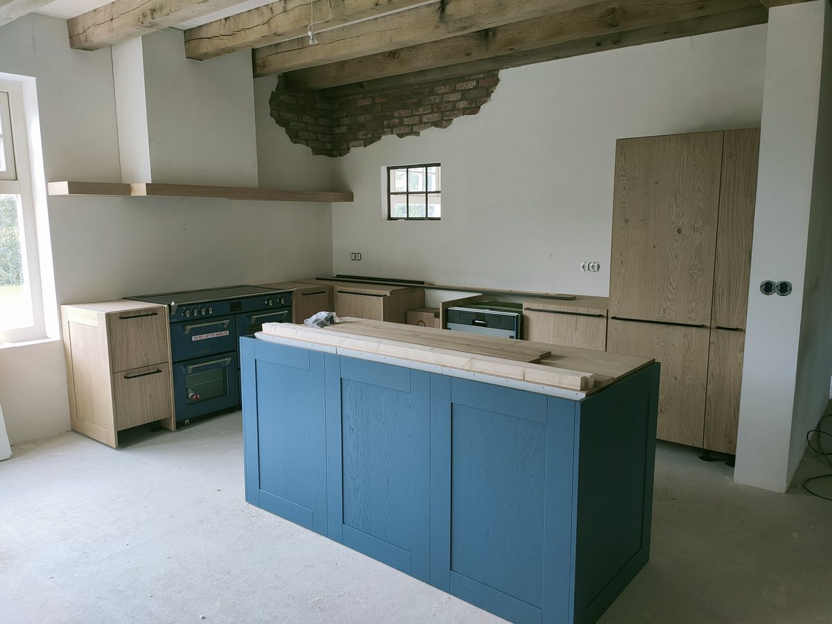 Blauw kookeiland en houten kastenwand in aanbouw, keuken op maat door het Tolhek