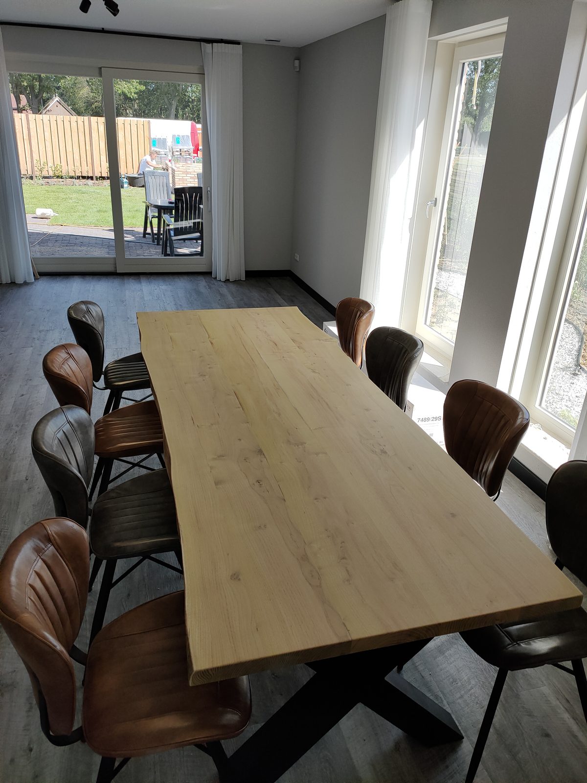 Massief eiken eettafel op maat met zwart kruisonderstel en leren stoelen